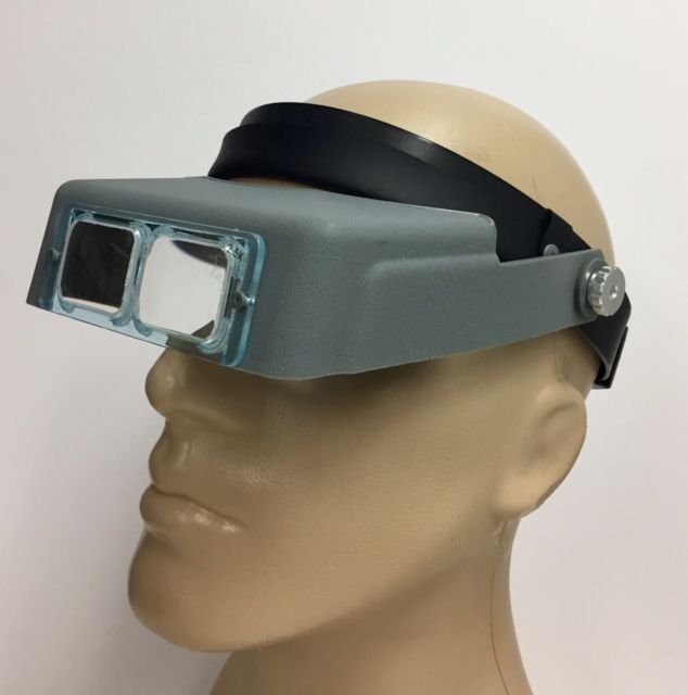 Headband magnifier shown on head with glass 2.5x standard lens.