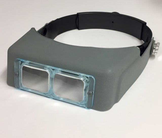 Headband magnifier shown  lying at an angle with glass 2.5x standard lens.